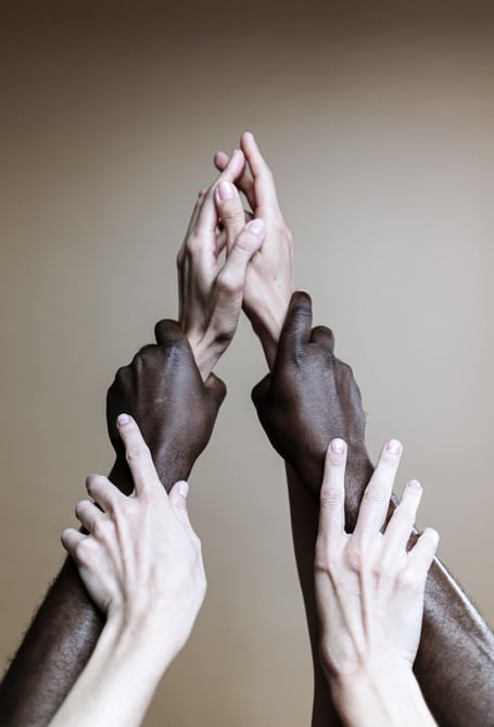 People holding hands and raising each other like a community. 