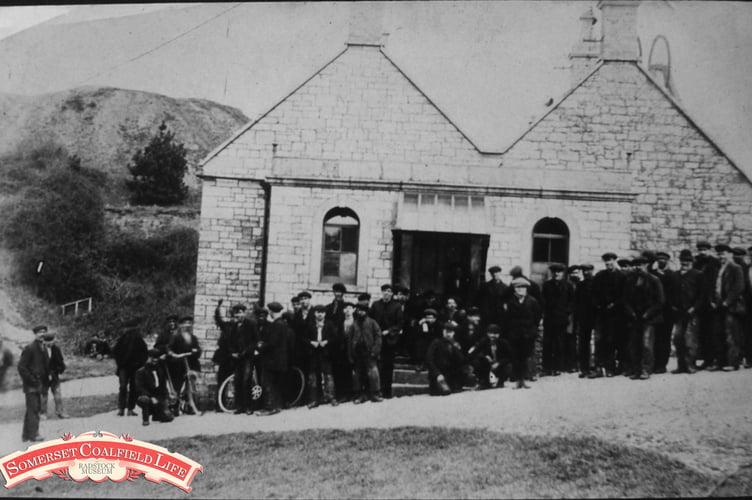 Can you tell us where we are in this week’s Mystery Photograph, and who the group of people are?