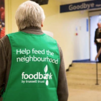 Somer Valley Foodbank volunteer welcomes customers. 