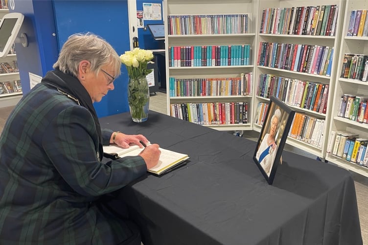 Mayor Lynda Robertson signs her condolences in book for HM The Queen at Midsomer Norton Library.