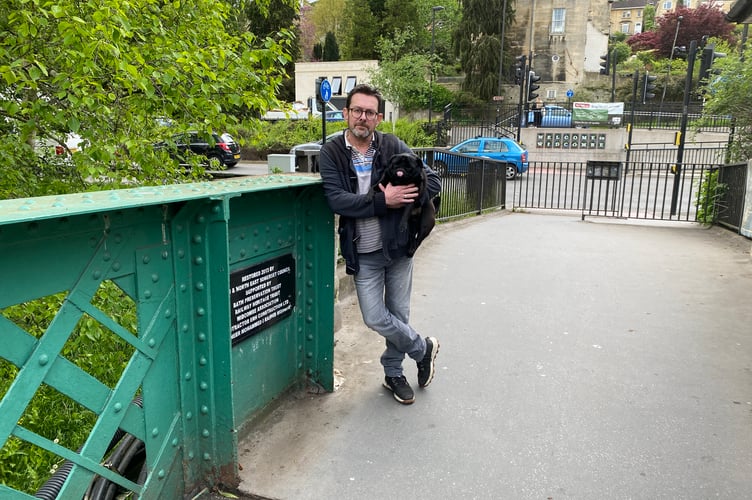 Casey Nolan, with his adopted pug Remington, next to the restoration plaque.
