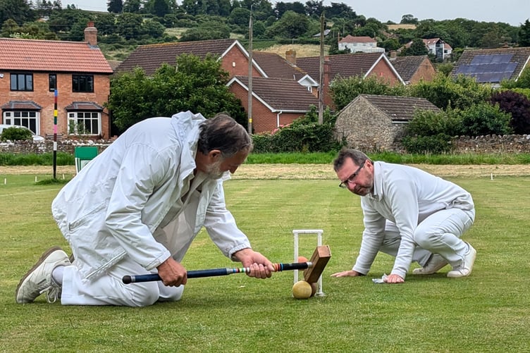 Phil Hendy on his knees playing a very tight, but ultimately successful, hoop shot. Nigel Wulko, as a qualified referee, observes the shot closely