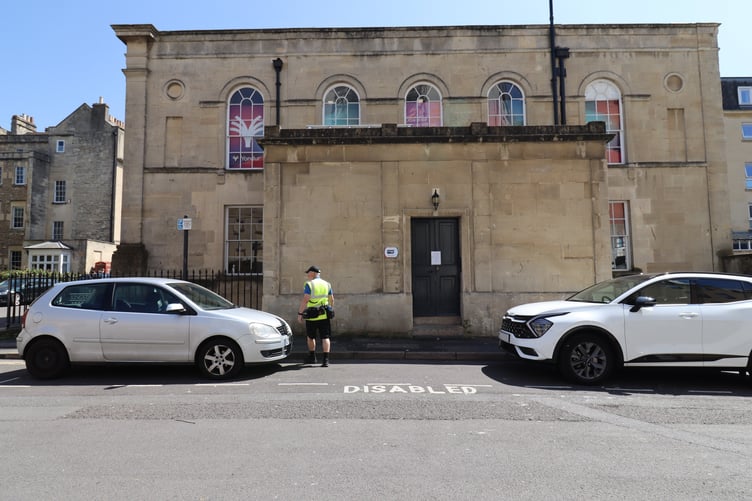 A Civil Enforcement Officer checking vehicles on Kingston Road, Bath.