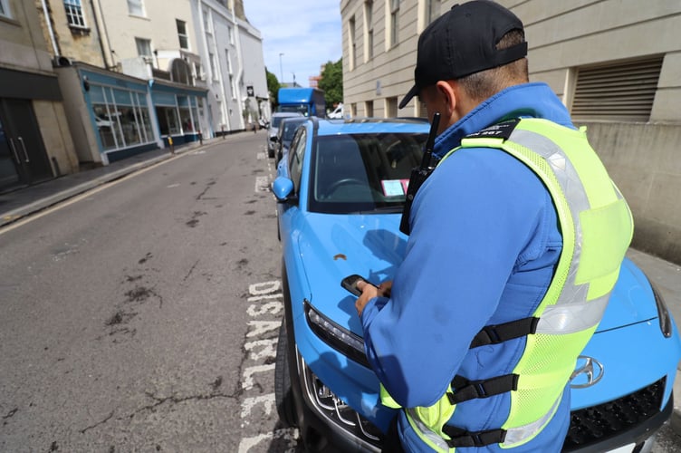 A B&NES Council Civil Enforcement Officer checking a vehicles Blue Badge.
