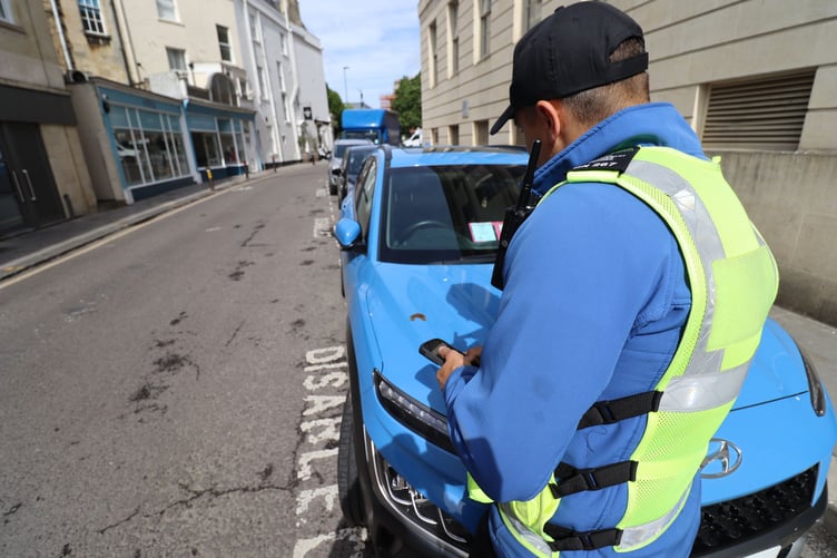 A B&NES Council Civil Enforcement Officer checking a vehicles Blue Badge.
