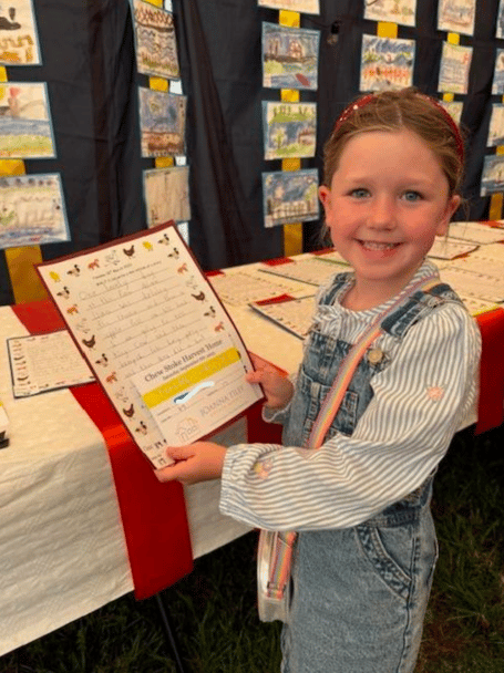 A proud Chew Stoke Church School pupil shows off her work, which formed part of this year's 'Harvest Home'