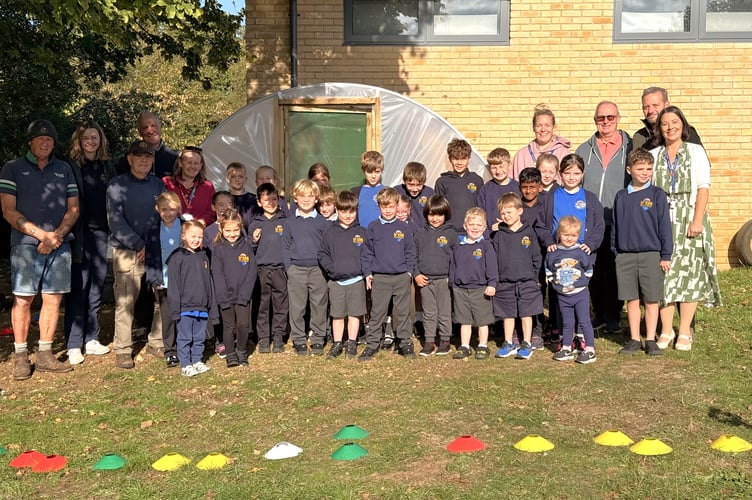 Cllr Gavin Heathcote (second right) with Headteacher Ruth Noall (right) along with volunteers, staff and pupils next to the new school polytunnel.
