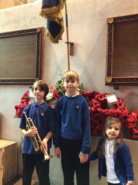 Pupils from Chew Magna Primary School stand in silence at the war memorial as a Year 6 pupil plays the Last Post on the trumpet.