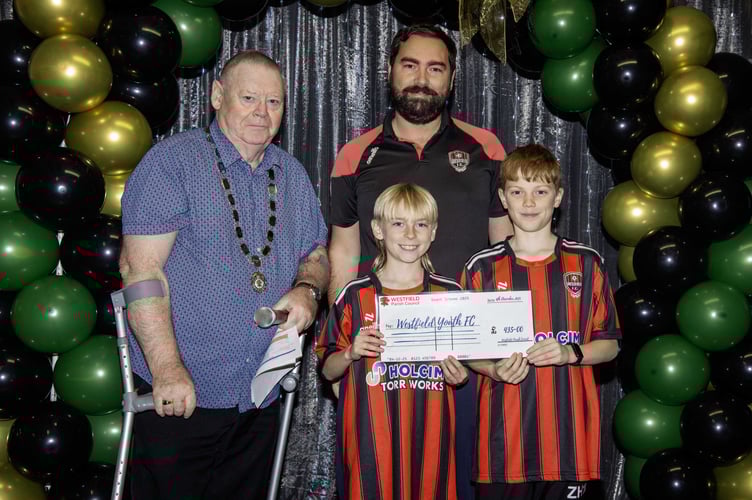 Westfield Youth FC representatives collecting £435 in funding from Westfield Parish Council chairman Cllr Phil Wilkinson