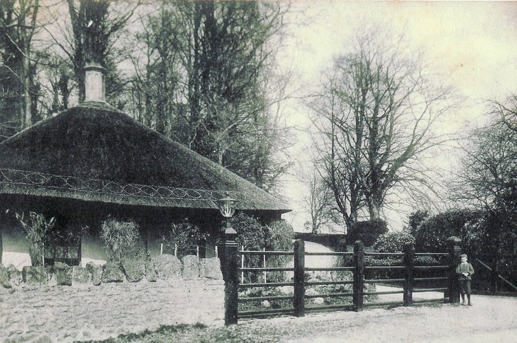 A young boy having his picture taken by a thatched cottage in bygone days, but where?