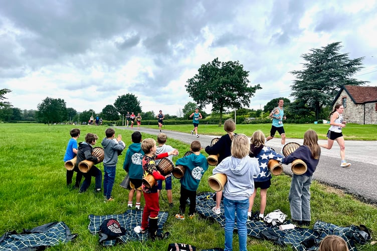Bishop Sutton Primary School pupils beating African drums on Widcombe Common to encourage runners.